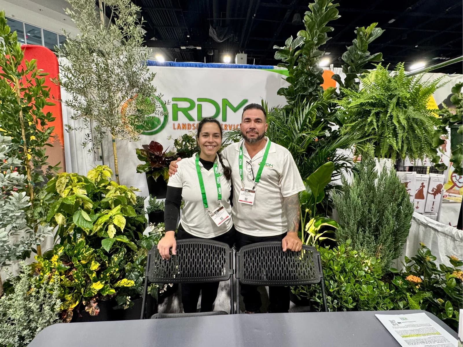 The RDM family team at their trade-show booth, surrounded by plants from the nursery